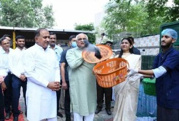 At a Shree Danev Foundation event, a diverse group of people, some adorned in traditional clothing and others in casual attire, gather outdoors to release birds from baskets.