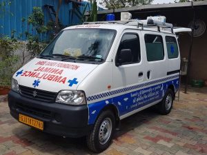 An ambulance parked on a brick road near a blue and white sign, indicating the Shree Danev Foundation Animal Hospital.